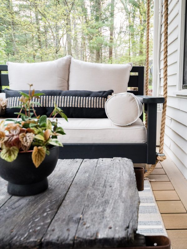 outdoor home decor featuring a swinging outdoor bench and greenery