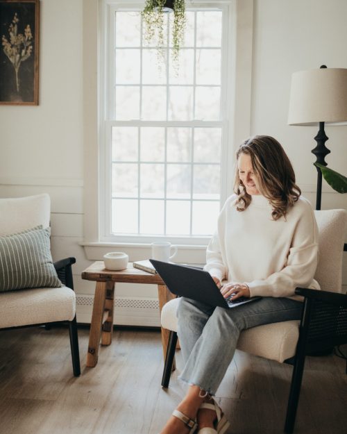 Dianne, cofounder of Only Prettier Design and the Found Her podcast, sits and works on her laptop, looking at their wedding, floral, and interior design projects