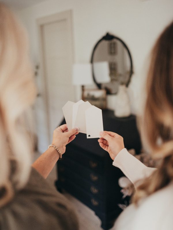 Heather and Dianne, founders of Only Prettier Design and the Found Her Podcast, hold paint swatches to help an interior design client with their paint color selection