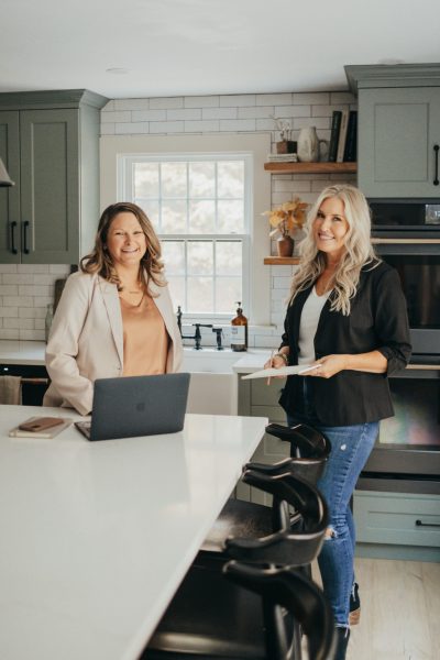 Dianne and Heather, founders of Only Prettier Design and the Found Her Podcast, stand in a renovated kitchen, ready to assist their next client