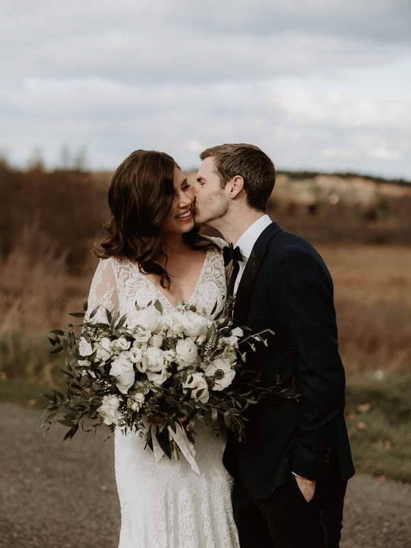 bride and groom holding a beautiful wedding bouquet of white flowers